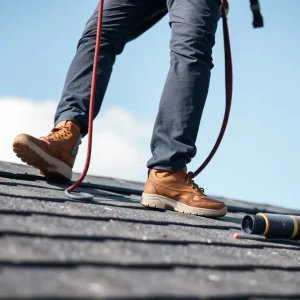 Person working on a sloped roof with safety harness