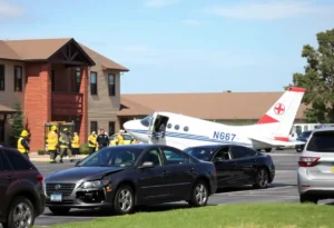 Scene of a small plane crash in a retirement community parking lot with emergency services responding.